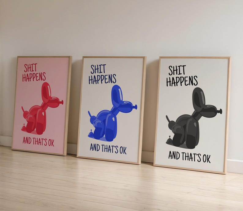 May include: Three framed art prints with the text "SHIT HAPPENS AND THAT'S OK". Each print features a balloon dog in red, blue, and black. The prints have a light wood frame and are leaning against a white wall.