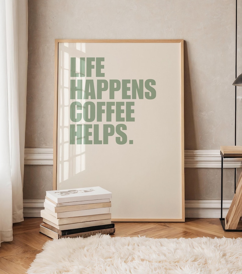 May include: A framed print with a light beige background and green text that reads "Life Happens Coffee Helps."