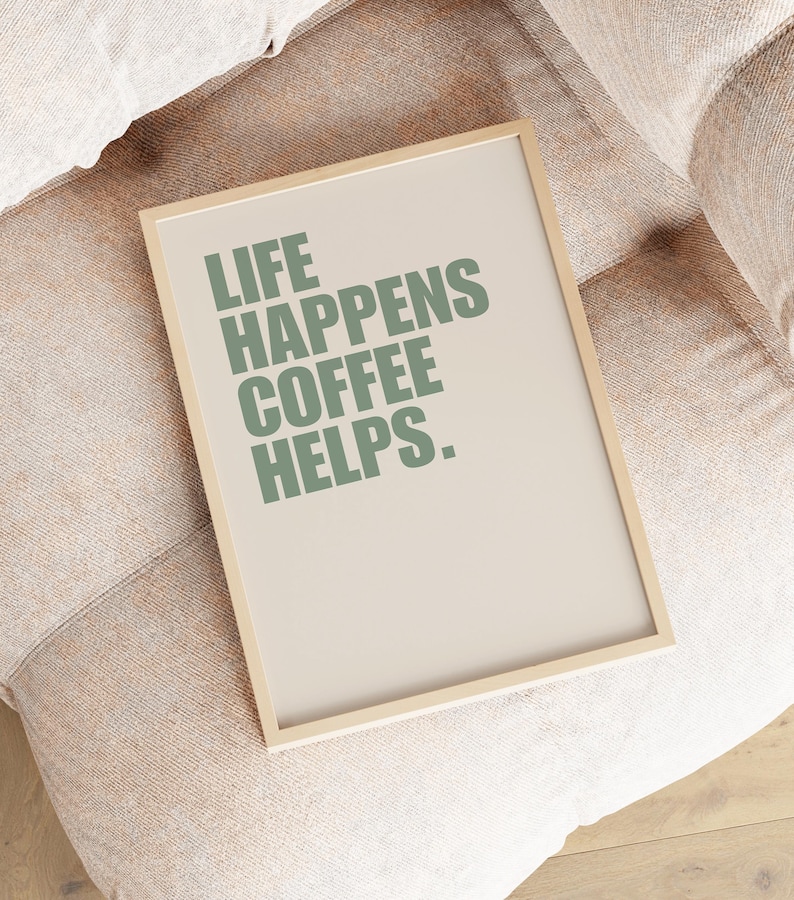 May include: A framed print with the text "Life Happens Coffee Helps." in green lettering on a beige background.