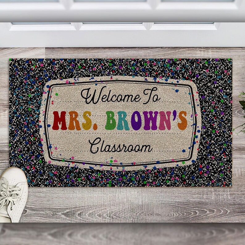 May include: Welcome to Mrs. Brown's Classroom doormat with a black background and colorful confetti. The text is in a white frame with a burlap texture.
