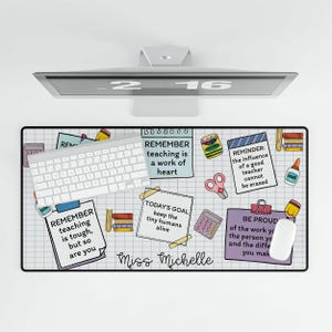 May include: A colorful desk mat with a grid pattern and inspirational quotes for teachers. The quotes include "Remember teaching is a work of heart", "Today's Goal: Keep the tiny humans alive", "Reminder: The influence of a good teacher cannot be erased", and "Be proud of the work you do, the person you are, and the difference you make". The mat also features a calculator, scissors, crayons, glue, and books.