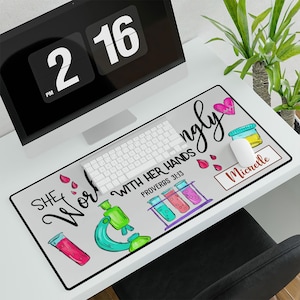May include: A gray and white mousepad with a colorful design featuring a microscope, test tubes, and the text "She Works Wonderfully With Her Hands Proverbs 31:13". The mousepad also has a pink heart and a brown name tag with the name "Michelle" on it.