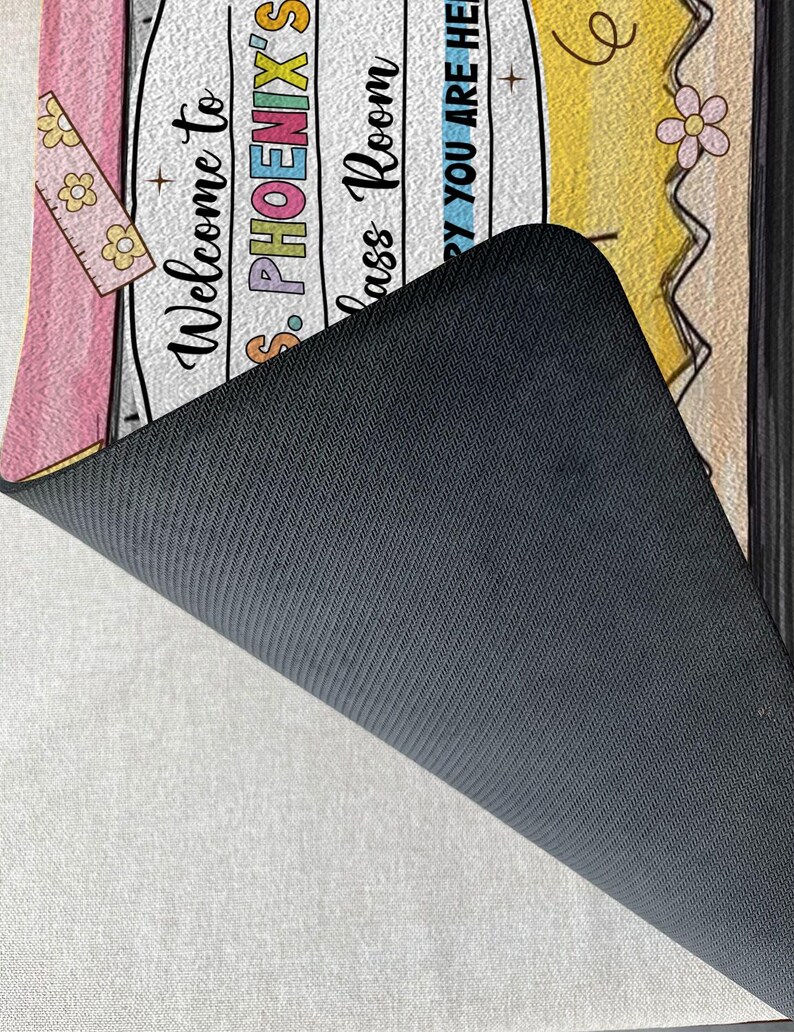May include: Welcome to Ms. Phoenix's Class Room doormat with a pink, yellow and white design. The doormat has a black backing.