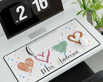 May include: White desk mat with colorful confetti and three hand-drawn hearts. The text "Mrs. Anderson" is written in black at the bottom of the mat.