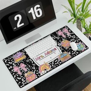 May include: Black and white desk mat with a school bus, books, and a globe design. The text "Mrs. Adams" is featured on the mat.