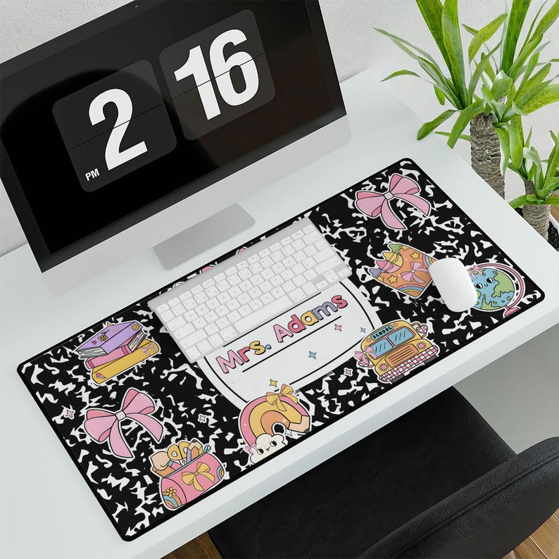 May include: Black and white desk mat with a school bus, books, and a globe design. The text "Mrs. Adams" is featured on the mat.