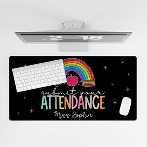 K&ouml;nnte beinhalten: Schwarze Schreibtischunterlage mit einem Regenbogen, einem Apfel und dem Text "Submit your Attendance Miss Sophia".