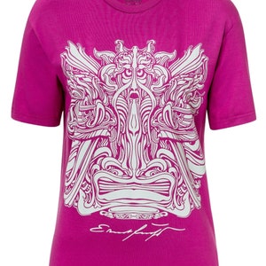 Op de afbeelding: Een magenta T-shirt met een wit, ingewikkeld grafisch ontwerp op de voorkant. Het ontwerp toont een gestileerd gezicht met wervelende patronen en de tekst "VALENTINA" bij de halslijn. De handtekening "Ernst Fuchs" staat onderaan.