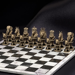 Könnte beinhalten: Ein komplettes Schachspiel mit aufwendig geschnitzten Tierfiguren. Die Schachfiguren umfassen Elefanten, Pferde, Gorillas, Adler und Löwen, die auf einem schwarz-weiß karierten Marmorbrett stehen. Die Figuren sind beige und braun.