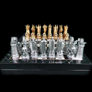 May include: A silver and gold chess set with a black marble board. The chess pieces are detailed and intricate, with a medieval theme.