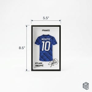 Peut inclure: Un cadre pr&eacute;sentant un maillot de football bleu et noir &agrave; motifs avec le nom MBAPPE et le num&eacute;ro 10. Le texte FRANCE et KYLIAN MBAPP&Eacute; figurent &agrave; c&ocirc;t&eacute; d'une signature. Le cadre mesure 13,97 cm de largeur et 21,59 cm de hauteur.