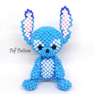 May include: A blue and pink beaded Stitch character with black eyes. The character is sitting with its legs crossed and its arms at its sides.