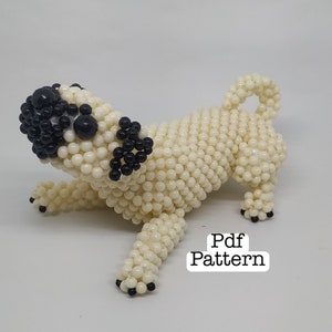 Può includere: Una statuetta di un carlino in perline bianche con occhi in perline nere. La statuetta è in posa in una posizione di corsa giocosa. L'immagine include il testo "Pdf Pattern".