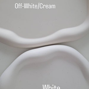 May include: Two ceramic trays, one off-white and one white. The off-white tray has the text "Off-White/Cream" written on it. The white tray has the text "White" written on it.