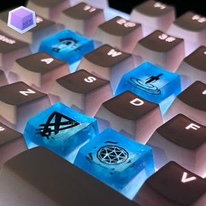 Könnte beinhalten: Nahaufnahme einer Tastatur mit blauen Tastenkappen mit verschiedenen Designs. Die Tastenkappen sind durchscheinend blau mit schwarzen Designs. Die Designs umfassen ein Schwert in einem Kreis, einen Diamanten mit Linien und ein Symbol mit einem Dreieck und Linien.