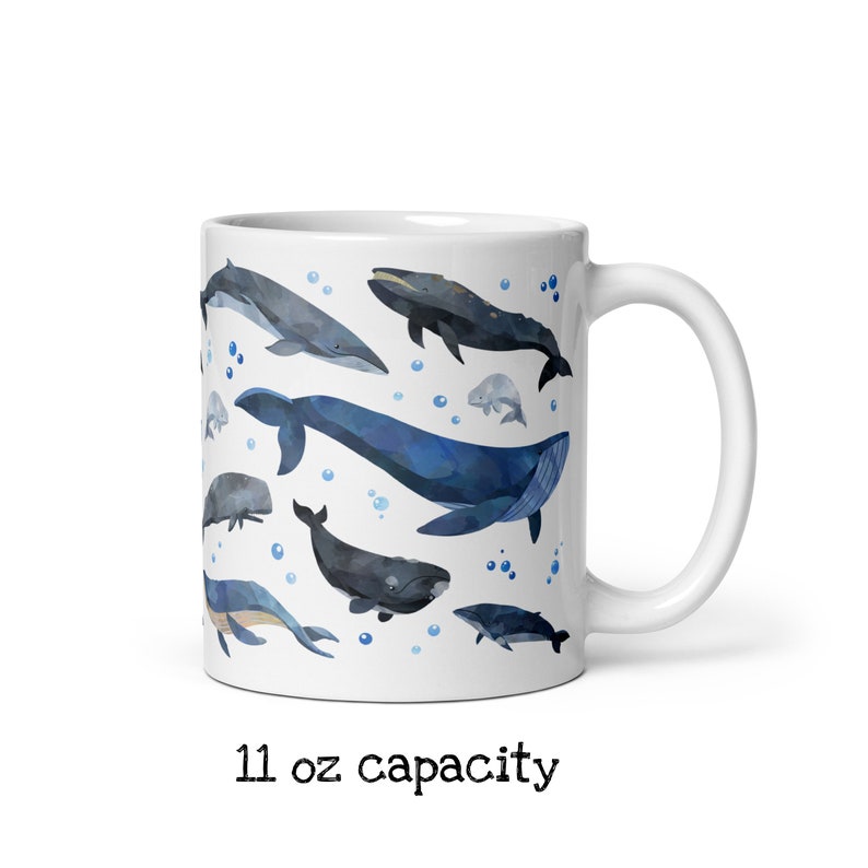 May include: White ceramic mug with a blue and gray watercolor design of various whales and dolphins. The mug has a 11 oz capacity and a black text label that reads "11 oz capacity".