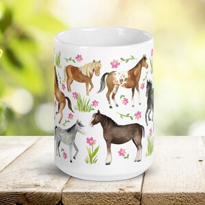 May include: White ceramic mug with a colorful pattern of horses and pink flowers. The horses are brown, black, white, and brown and white.