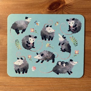 May include: A blue background with multiple illustrations of opossums in various poses. The opossums are grey and white with black eyes and noses. Some opossums are holding babies. There are also small flowers and leaves scattered around the opossums.