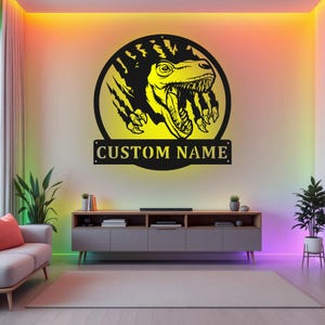 May include: A black metal wall decor featuring a yellow dinosaur head breaking through a wall with the text "CUSTOM NAME" below.