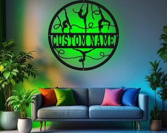 May include: A black metal circle with a green glow behind it. The circle features silhouettes of gymnasts in various poses. The text "CUSTOM NAME" is written across the middle of the circle.