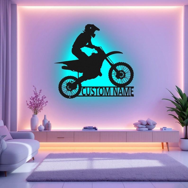 May include: Black silhouette of a motocross rider on a dirt bike with the text "CUSTOM NAME" below. The image is set against a wall with colorful LED lights.