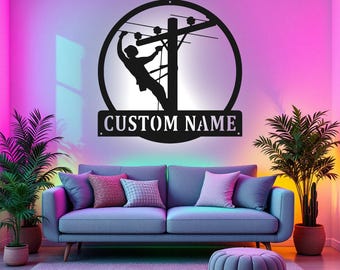 May include: A black metal silhouette of a lineman working on a power line, with the text "CUSTOM NAME" below. The silhouette is mounted on a wall with a pink and purple background.