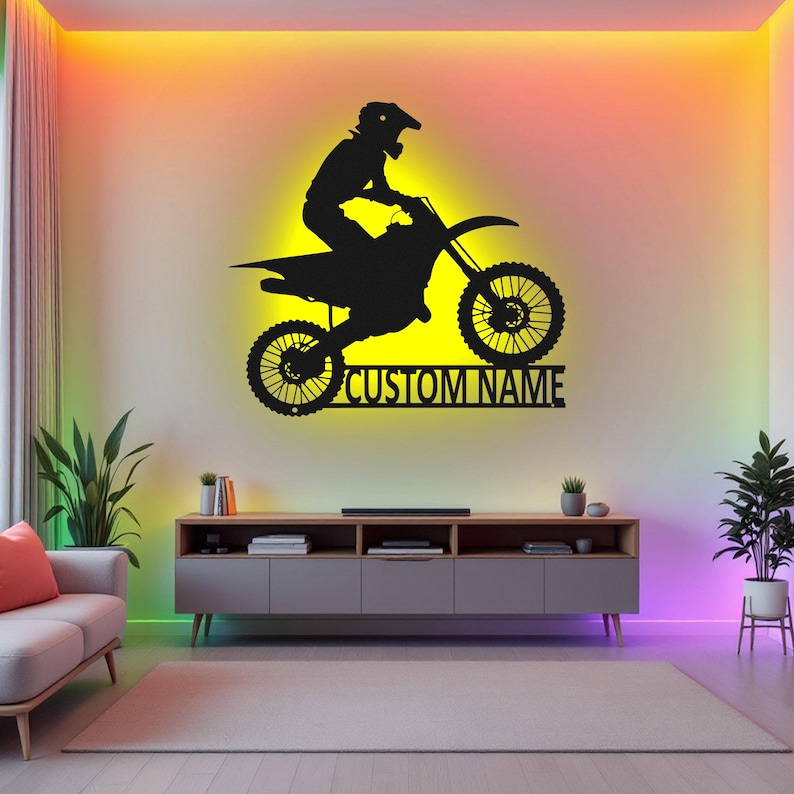 May include: Black silhouette of a motocross rider on a dirt bike with the text "CUSTOM NAME" below. The image is on a wall with colorful LED lights.