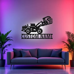 Könnte beinhalten: Schwarze Metallsilhouette eines Skid-Steer-Loaders mit einem Holzgreifer, mit dem Text "CUSTOM NAME" darunter.
