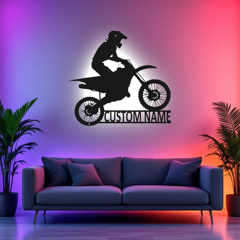 May include: A black silhouette of a motocross rider on a dirt bike with the text "CUSTOM NAME" below. The image is set against a wall with colorful lighting.
