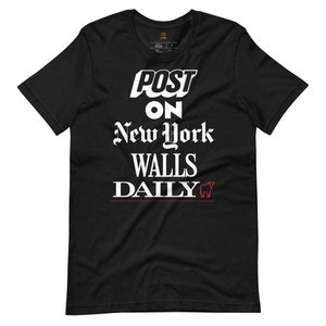 May include: Black t-shirt with white text that reads "POST ON NEW YORK WALLS DAILY" with a red bull graphic.