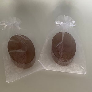 May include: Two oval-shaped wooden boxes wrapped in white tulle with white ribbon bows.