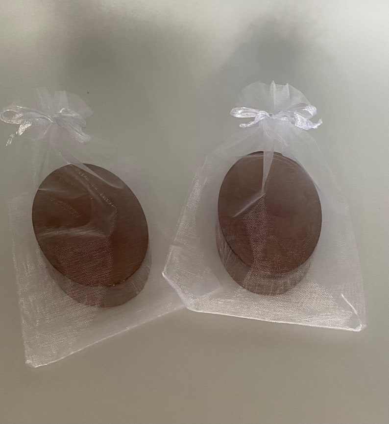 May include: Two oval-shaped wooden boxes wrapped in white tulle with white ribbon bows.