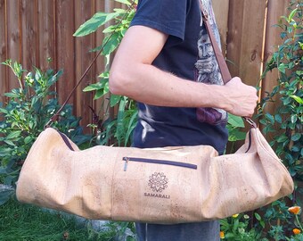 Puede incluir: Una bolsa de yoga de corcho marrón con una cremallera y un logotipo que dice "Samarali" en la parte delantera. La bolsa la lleva una persona.