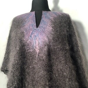 May include: A gray fuzzy knit poncho with a purple and blue design on the neckline.