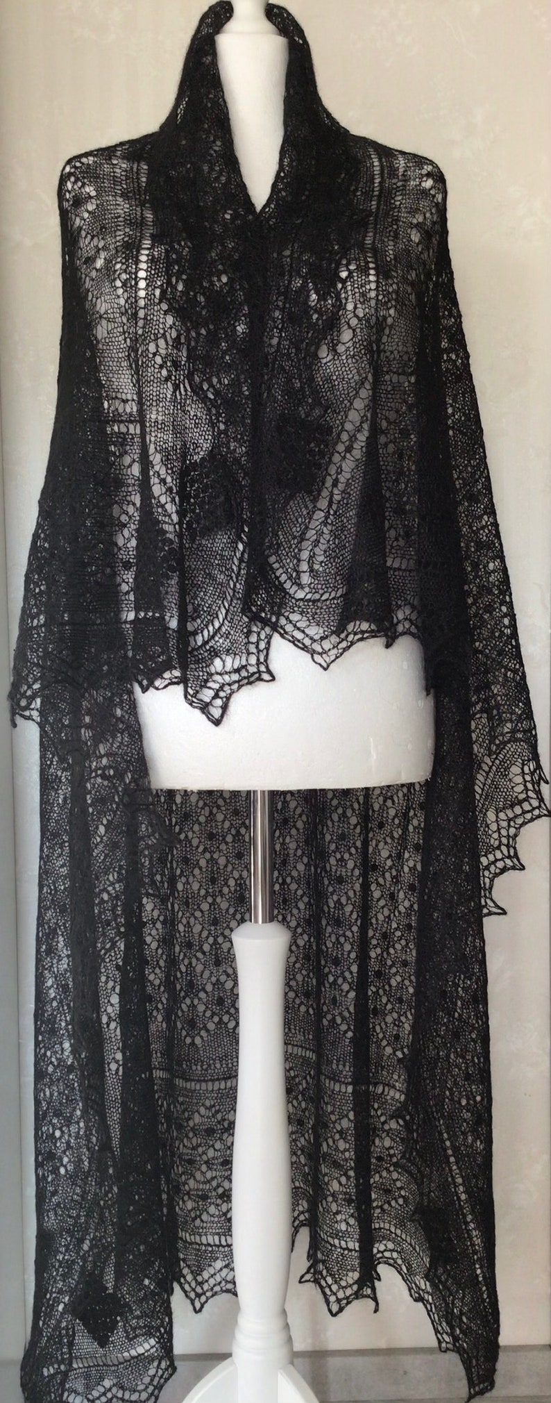 Puede incluir: Un chal de encaje negro con un patr&oacute;n delicado. El chal est&aacute; drapeado sobre un maniqu&iacute; blanco.