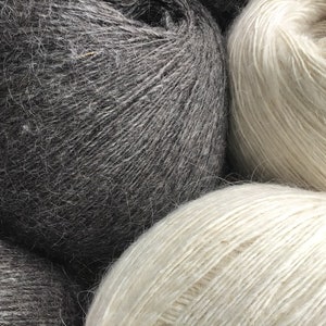 May include: Three balls of yarn, one black, one white, and one light gray. The yarn is soft and fluffy, and it is perfect for knitting or crocheting.