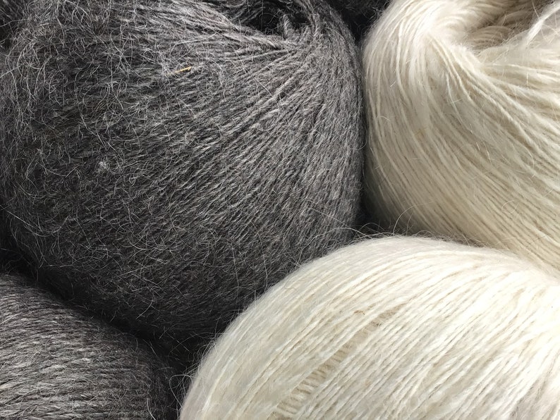 May include: Three balls of yarn, one black, one white, and one light gray. The yarn is soft and fluffy, and it is perfect for knitting or crocheting.