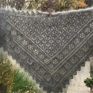 以下が含まれることがあります： レース模様のグレーとホワイトのクロシェのショールが物干し竿にかけられています