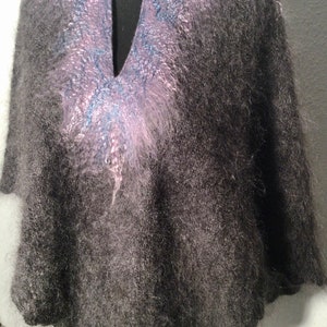 May include: A gray fuzzy knit poncho with a pink and blue design on the neckline.