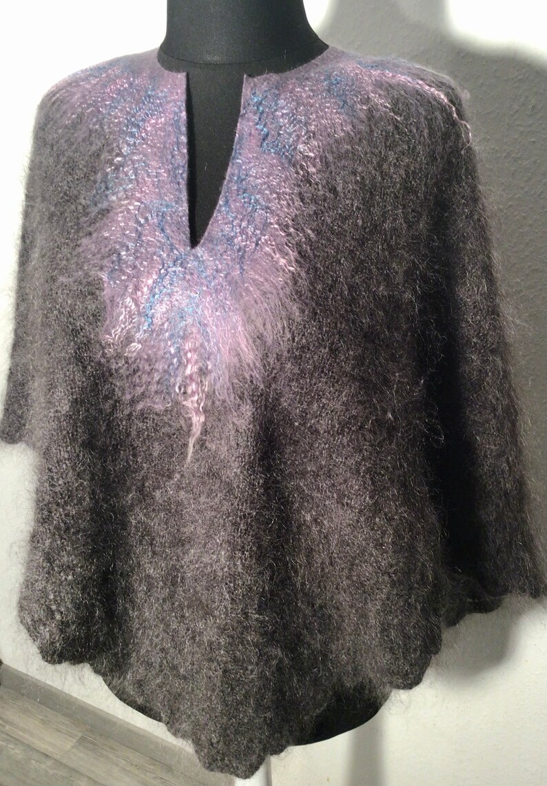 May include: A gray fuzzy knit poncho with a pink and blue design on the neckline.
