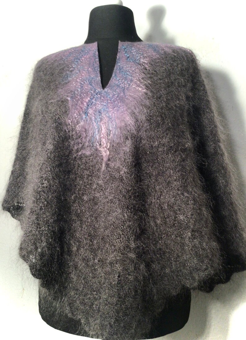 May include: A gray fuzzy knit poncho with a purple and blue design on the neckline.
