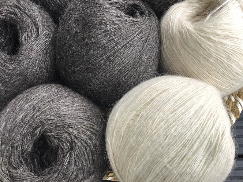 May include: Four balls of yarn, two are dark gray and two are light beige. The yarn is soft and fluffy.