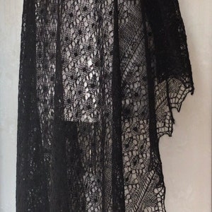 Puede incluir: Un chal de encaje negro con un patr&oacute;n delicado. El chal est&aacute; drapeado sobre un maniqu&iacute; blanco.