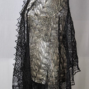 Puede incluir: Un chal de encaje negro con un delicado patr&oacute;n floral. El chal est&aacute; drapeado sobre un maniqu&iacute; blanco.