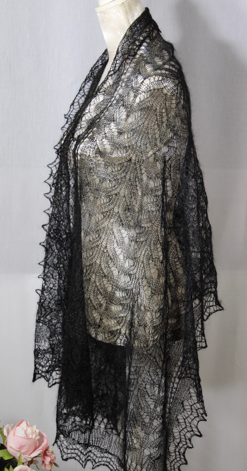 Puede incluir: Un chal de encaje negro con un delicado patr&oacute;n floral. El chal est&aacute; drapeado sobre un maniqu&iacute; blanco.