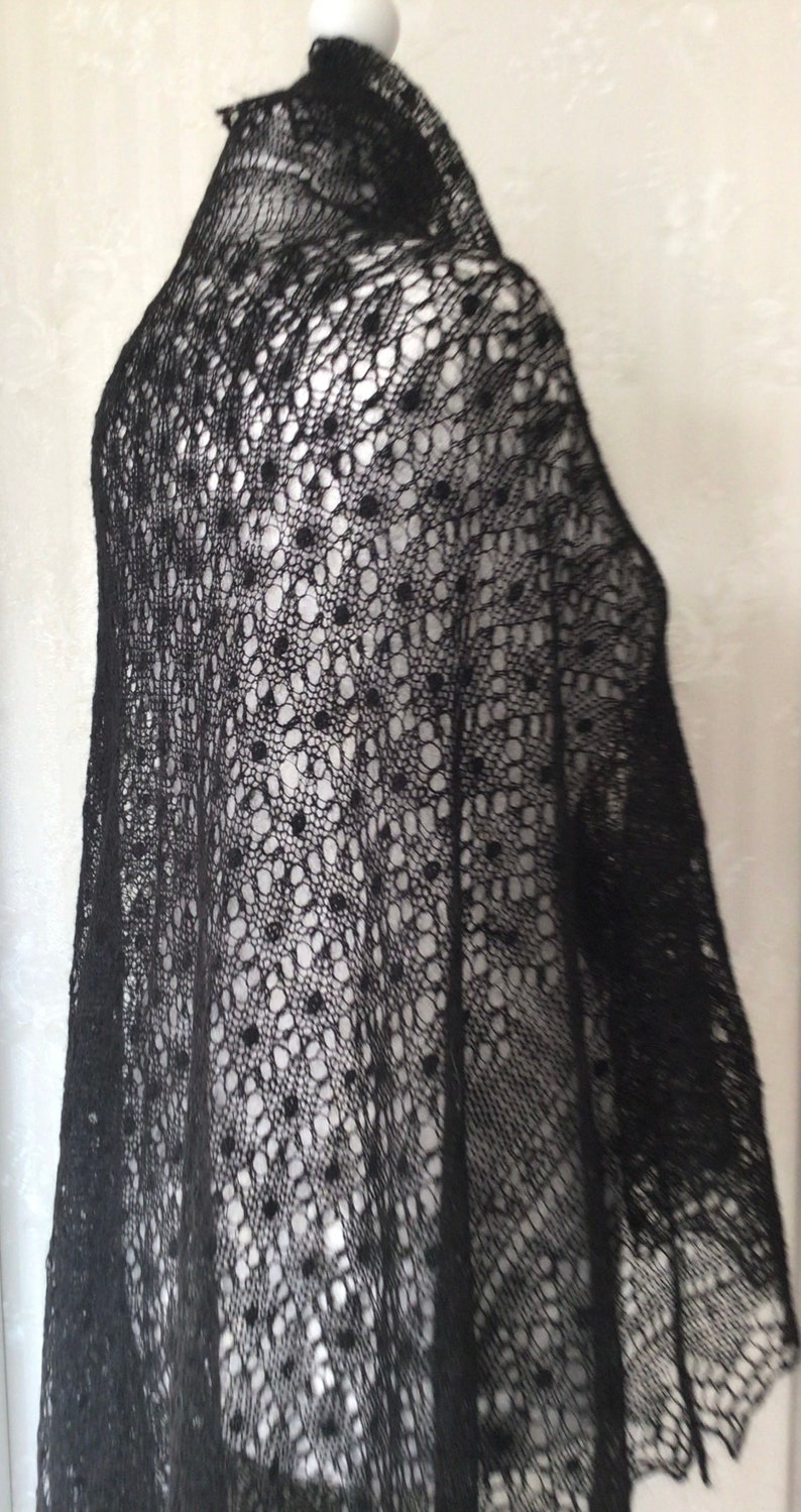 Puede incluir: Chale de encaje negro con un delicado patr&oacute;n de peque&ntilde;os c&iacute;rculos. El chal est&aacute; drapeado sobre un maniqu&iacute;.