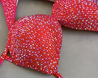 May include: Red bikini top with crystal embellishments. The top is made of a stretchy fabric and has a halter neck style.