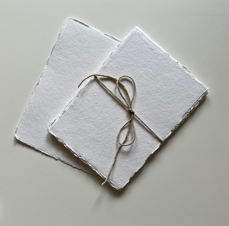 Peut inclure: Deux feuilles de papier fait main avec des bords festonn&eacute;s, li&eacute;es ensemble par un n&oelig;ud en ficelle naturelle.