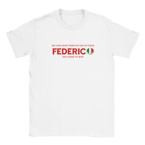 Puede incluir: Camiseta blanca con texto rojo. El texto dice "WE CAN HEAR THEM CRYING IN TURIN" encima del nombre "FEDERICO" en rojo. Debajo, "HE'S HERE TO WIN". Un gráfico de la bandera italiana está a la derecha.