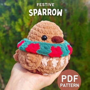 Könnte beinhalten: Ein handgefertigter Spatz aus braunem, cremefarbenem und blaugrünem Garn, mit einem roten und blaugrünen Schal. Der Text "FESTIVE SPARROW" steht über dem Vogel, und "PDF PATTERN" befindet sich in einer kreisförmigen Grafik.